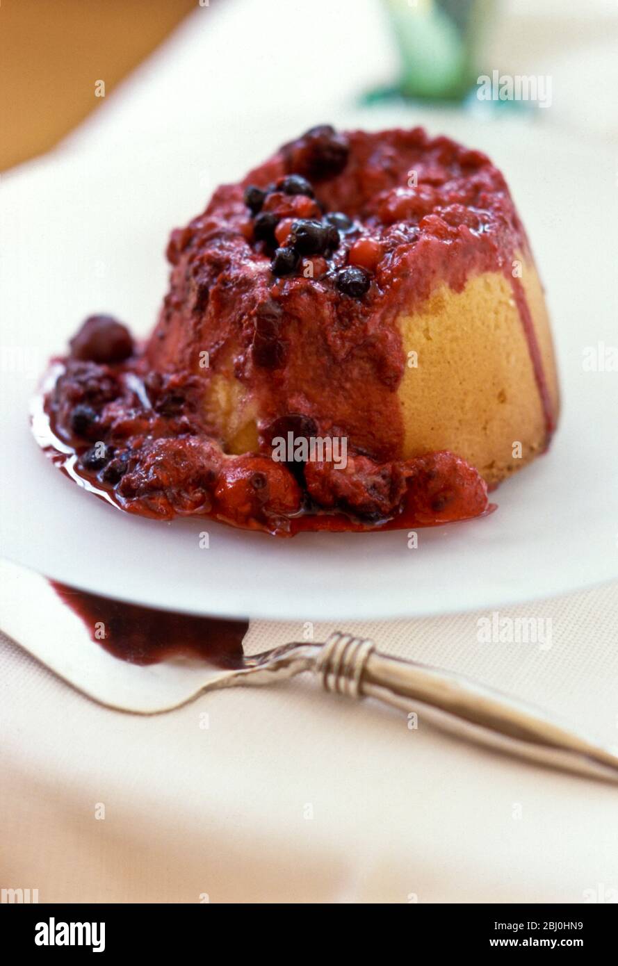 Steamed jam sponge pudding on white plate - Stock Photo