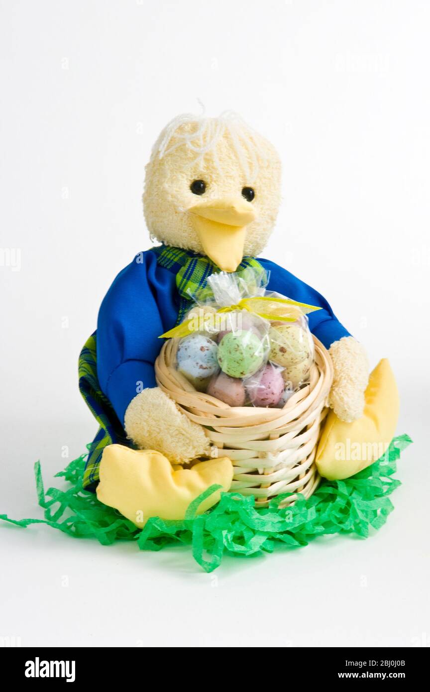 Cute duckling ornament with basket of candies as Easter gift. - Stock Photo