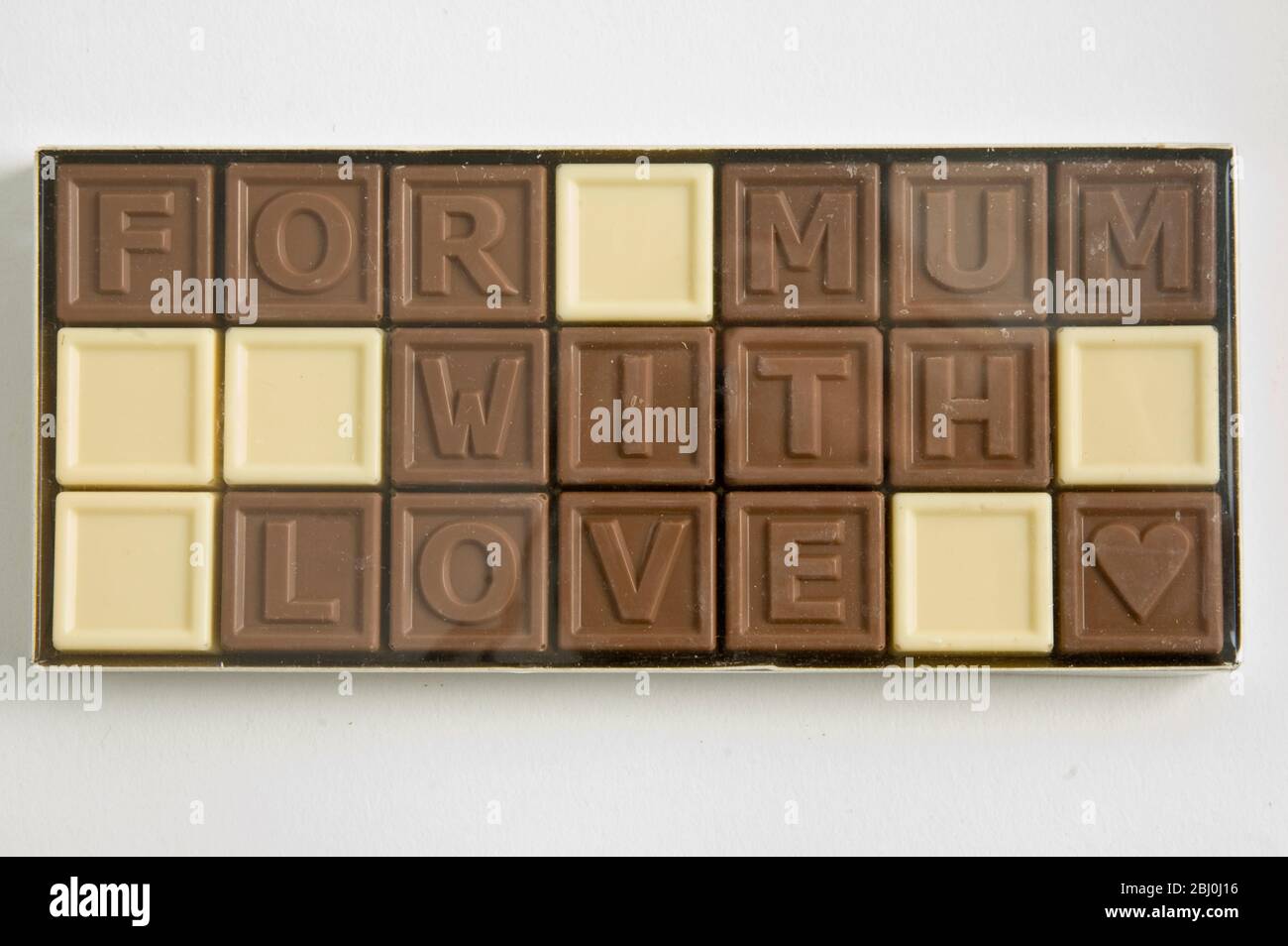 Chocolate letters spelling 'For Mum with love' in cellophane box as Mother's day gift - Stock Photo