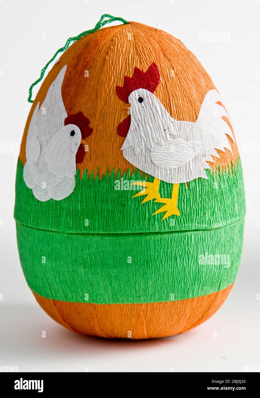 Decorative paper box shaped as Easter eggs with paper shapes of chickens stuck on with coloured crepe paper - Stock Photo