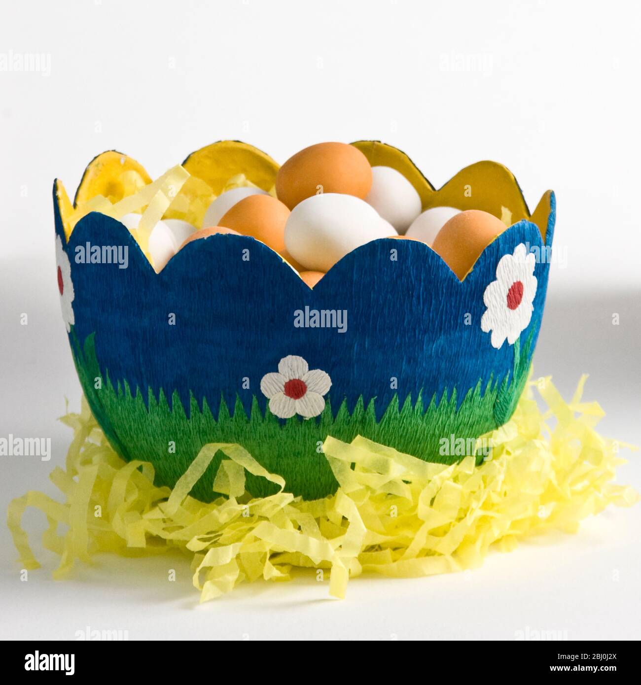 Egg shaped decorated paper bowl with sugar coated chocolate eggs - Stock Photo