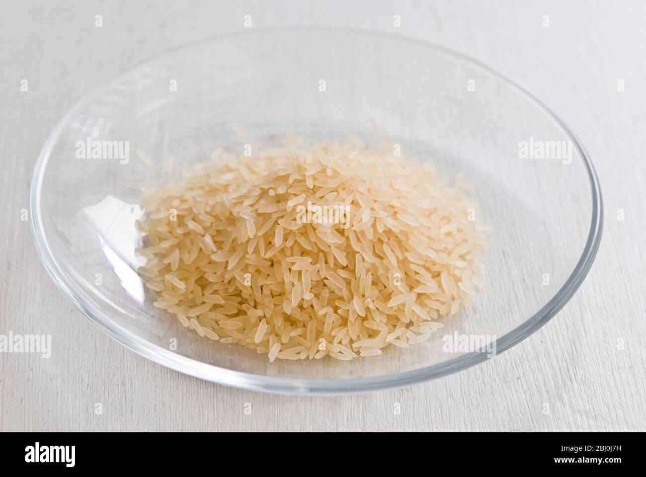 Small pile of natural longgrain rice on white background - Stock Photo