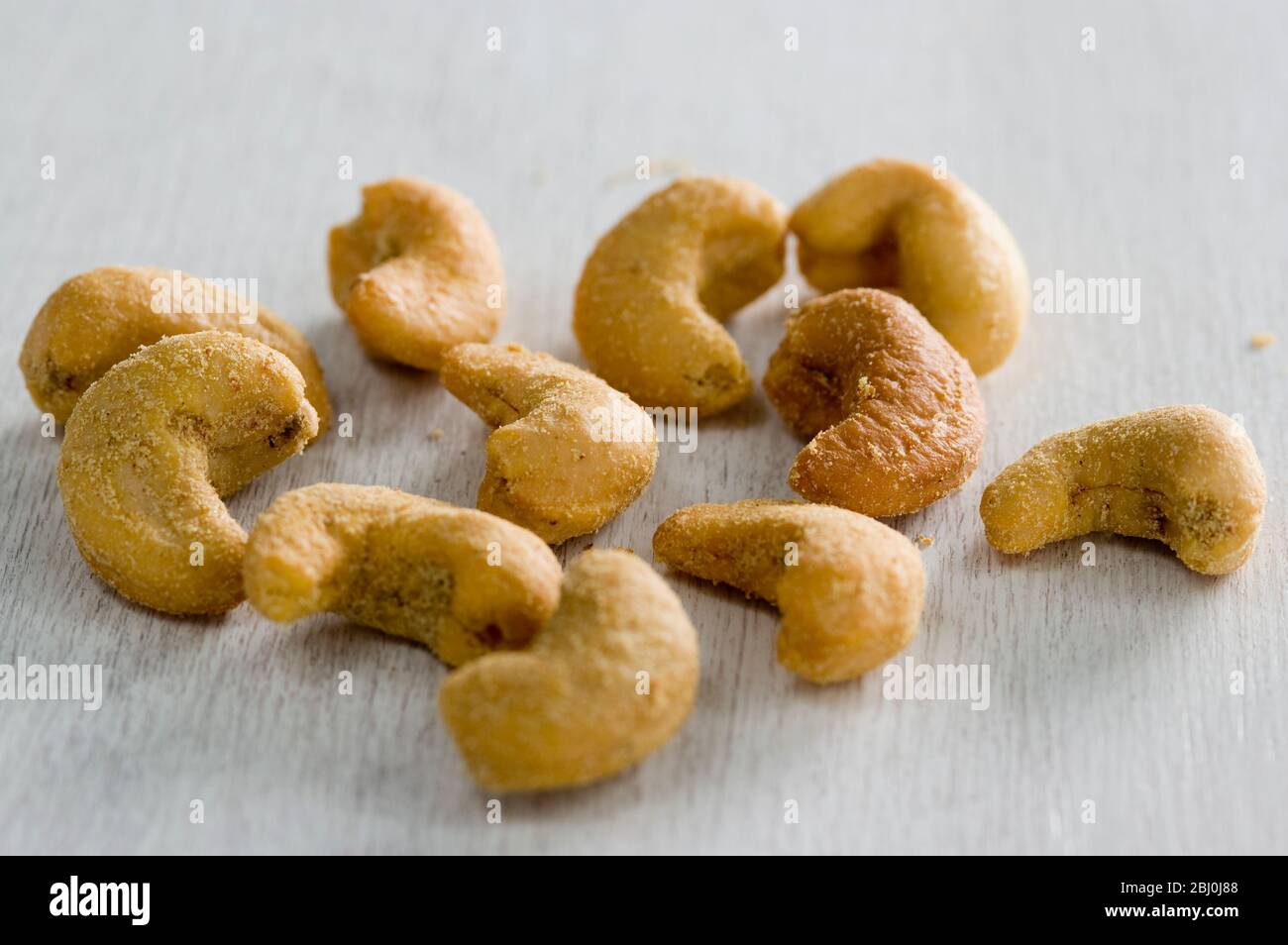 Slated cashew nuts in small pile in white surface - Stock Photo