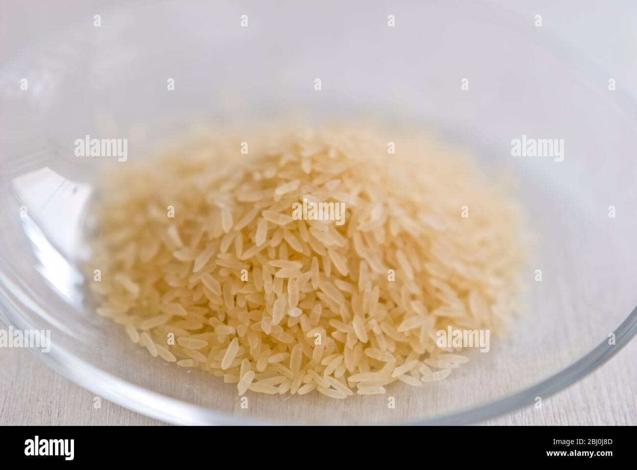 Small pile of natural longgrain rice on white background - Stock Photo