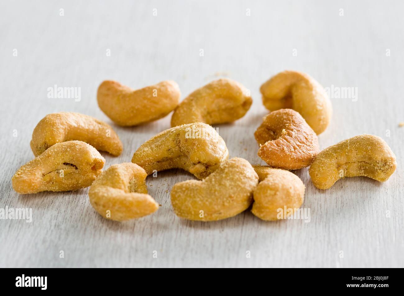Slated cashew nuts in small pile in white surface - Stock Photo