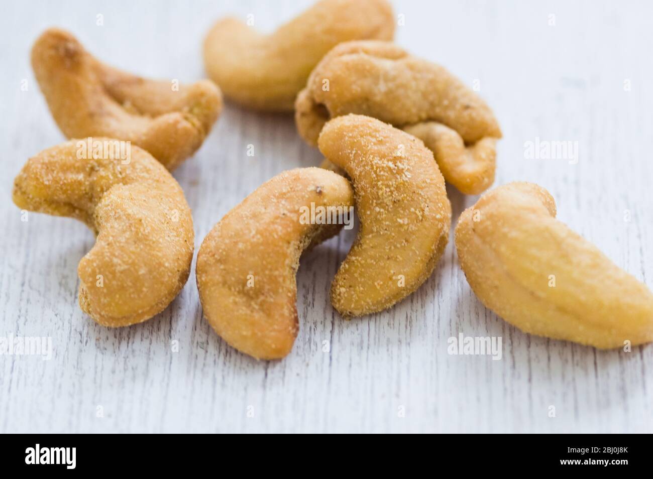 Slated cashew nuts in small pile in white surface - Stock Photo