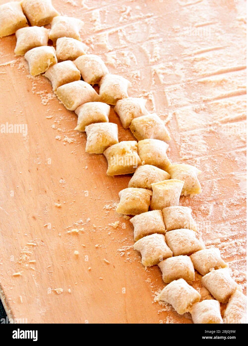 The two lengths of gnocchi dough rolled out into thinner 'sausage' and cut into equal pieces - Stock Photo