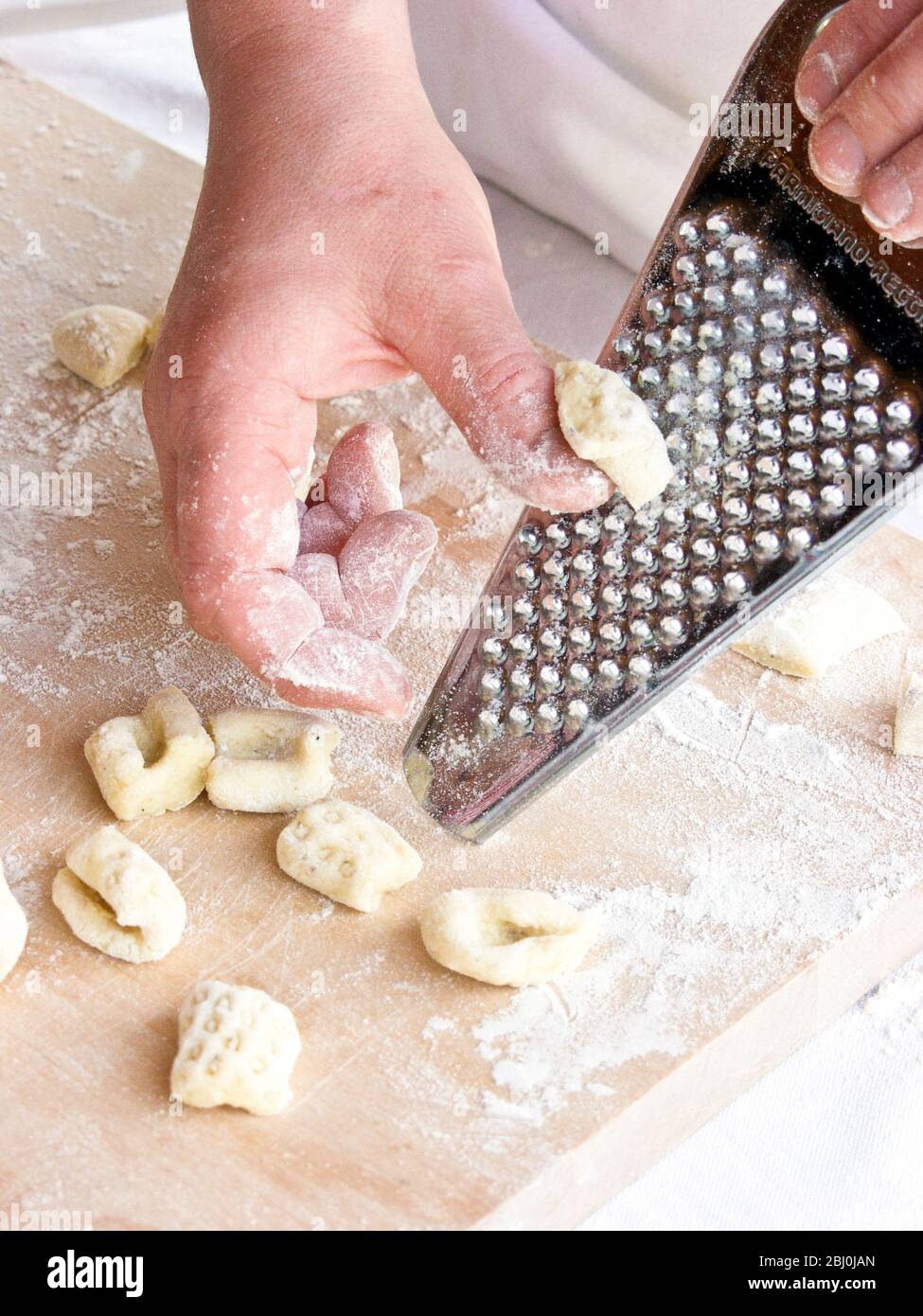 Rolling pieces of gnocchi dough on lemon zest grater, to shape them and give them texture. - Stock Photo