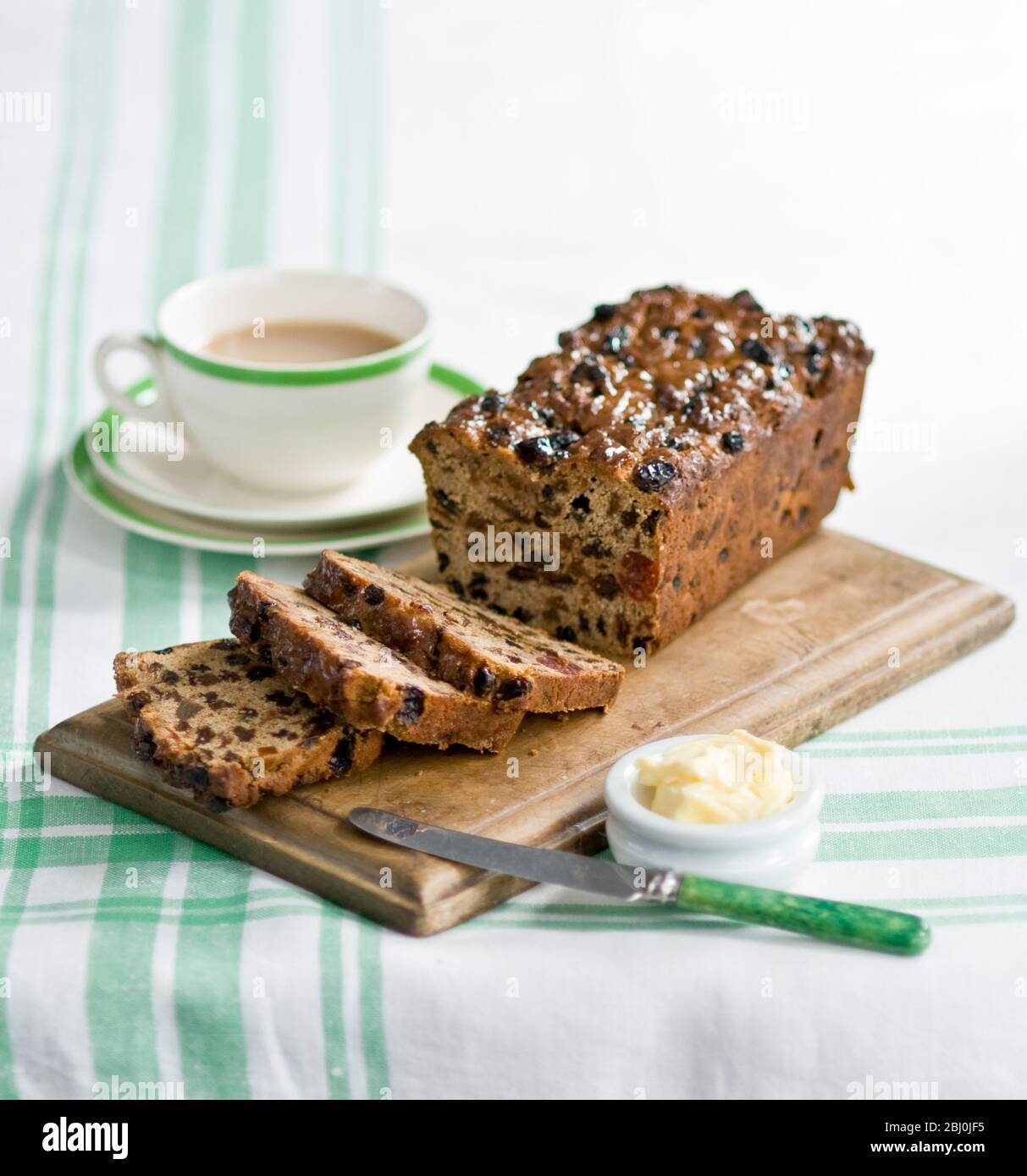 Traditional style fruit tea loaf sliced and served with butter and afternoon tea - Stock Photo