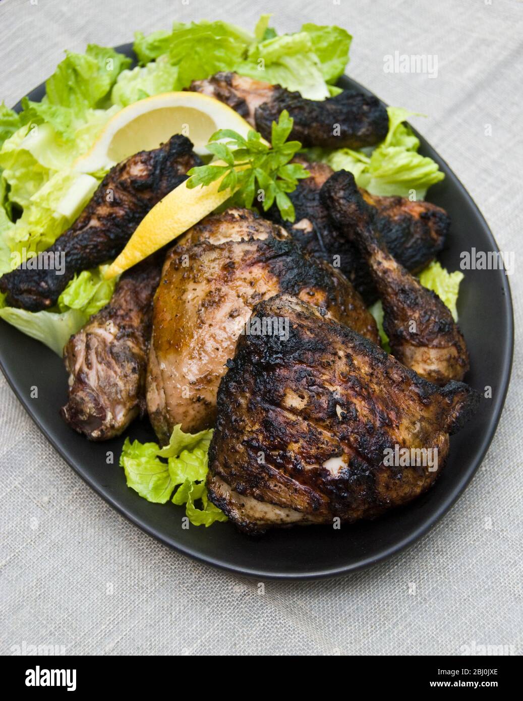 Chargrilled chicken legs on plater with salad outdoors - Stock Photo