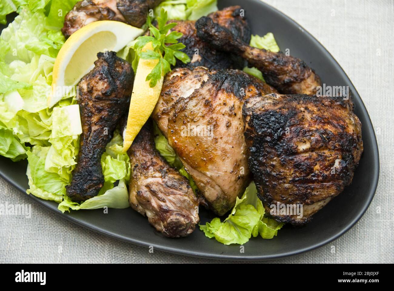 Chargrilled chicken legs on plater with salad outdoors - Stock Photo