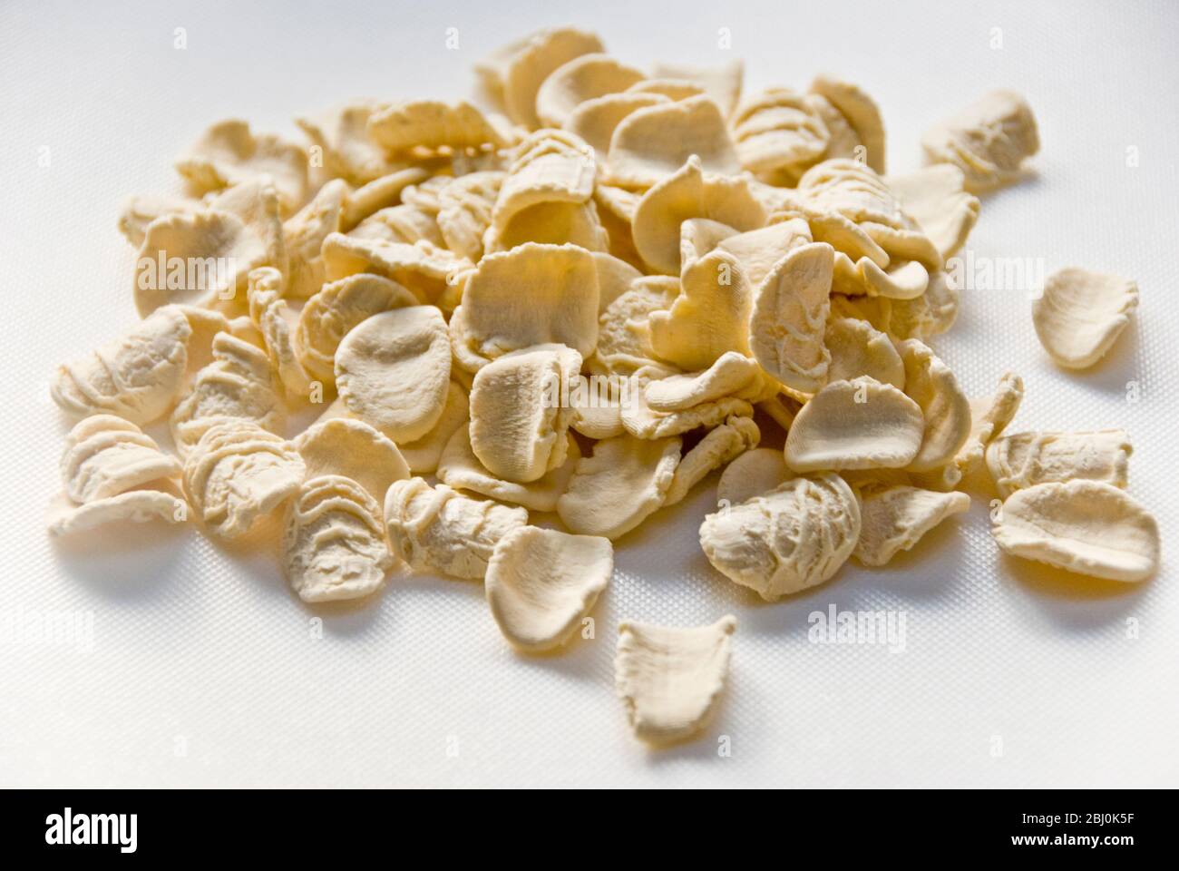 Dried, uncooked orecchiete pasta on white suface - Stock Photo
