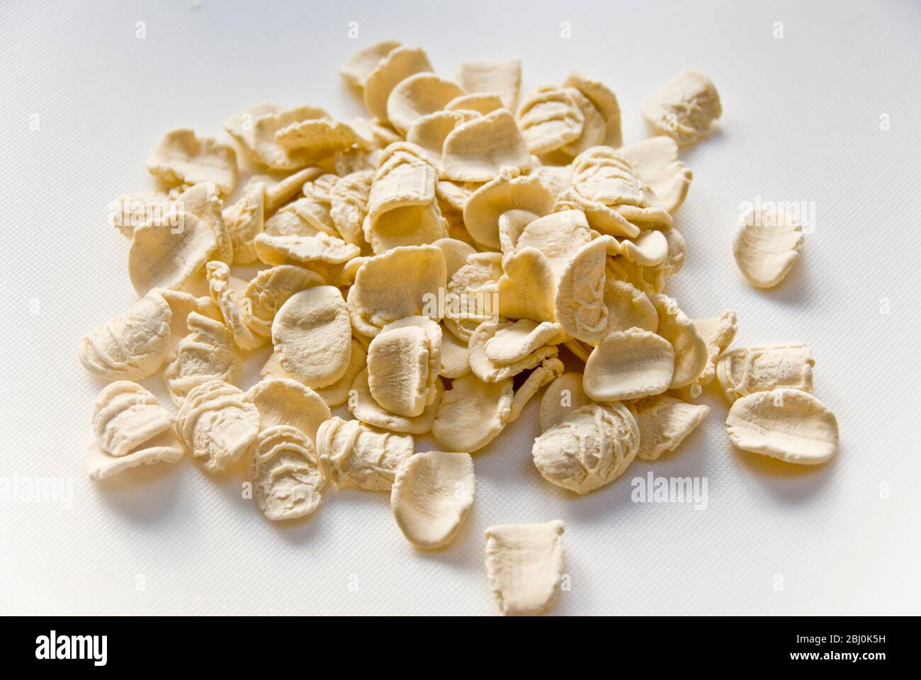 Dried, uncooked orecchiete pasta on white suface - Stock Photo