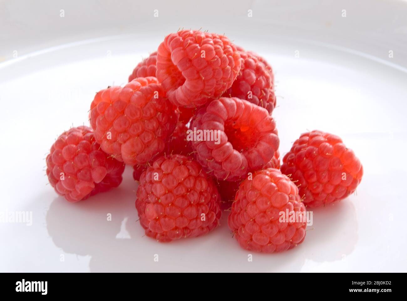 Fresh whole raspberries on white plate Stock Photo - Alamy