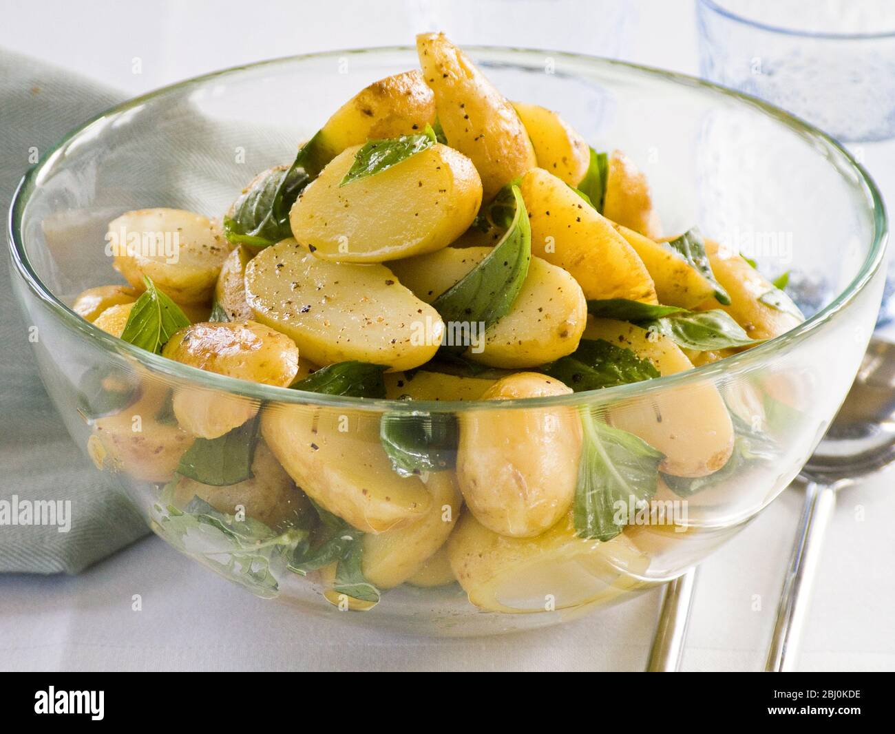 New potato salad in dressing of olive oil, wine vinegar and wholegrain mustard , with basil leaves - Stock Photo