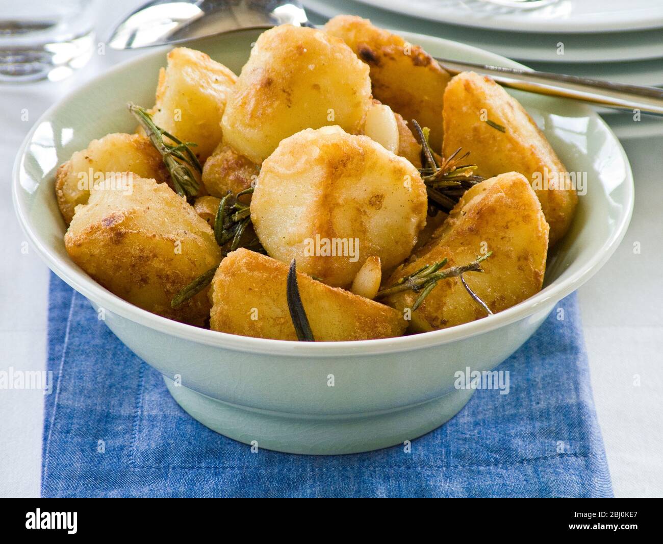 Roast potatoes with rosemary in green bowl - Stock Photo