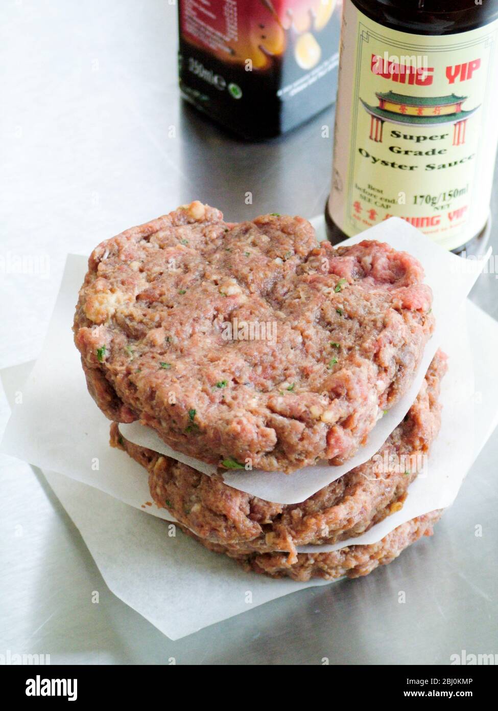 Home made uncooked hamburgers flavoured with chinese oyster sauce and chilli - Stock Photo