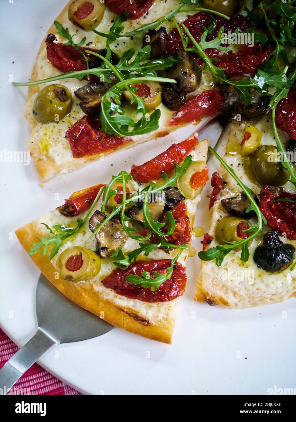 Pizza with sundries tomatoes, aubergine, olives, mozzarella and rocket