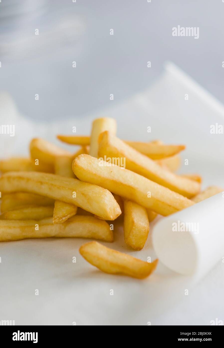Deep fried potato chips on greaseproof paper - Stock Photo