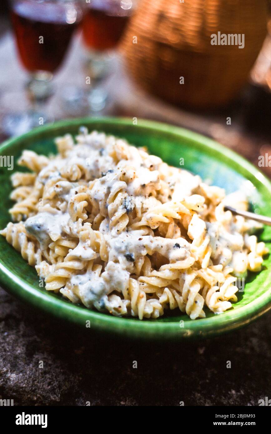 Dish of fusilli pasta with blue cheese creamy dressing on table outside - Stock Photo