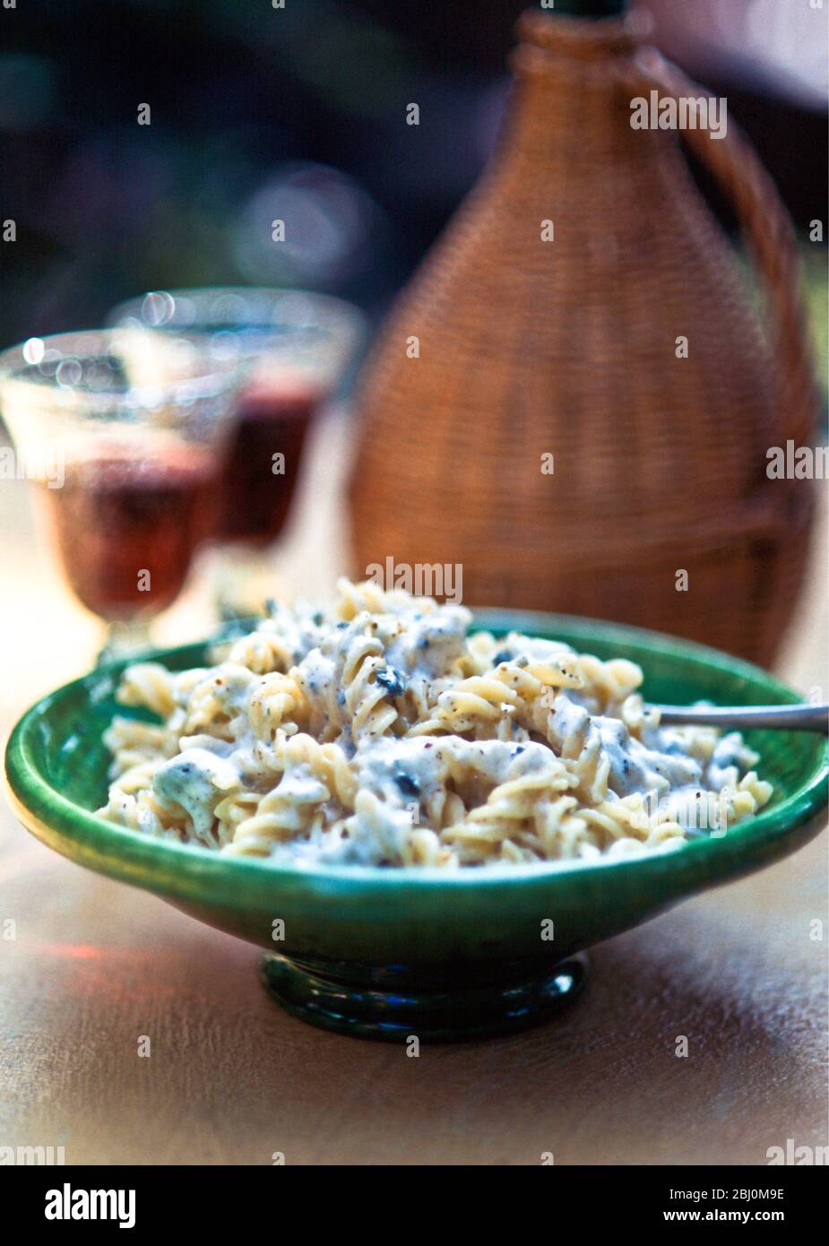 Dish of fusilli pasta with blue cheese creamy dressing on table outside - Stock Photo