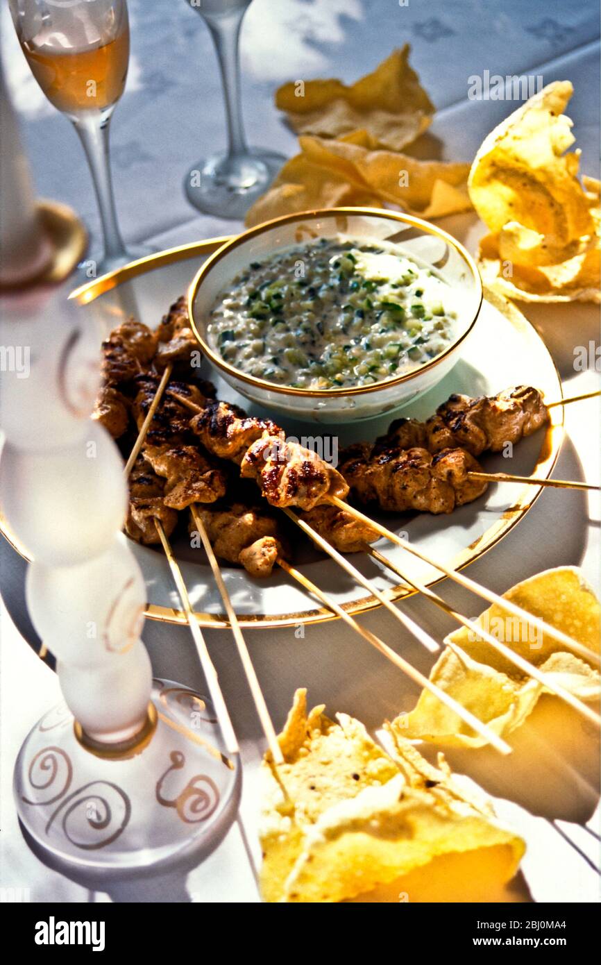Satay chicken sticks with raita and poppadums, outdoors in party setting. - Stock Photo
