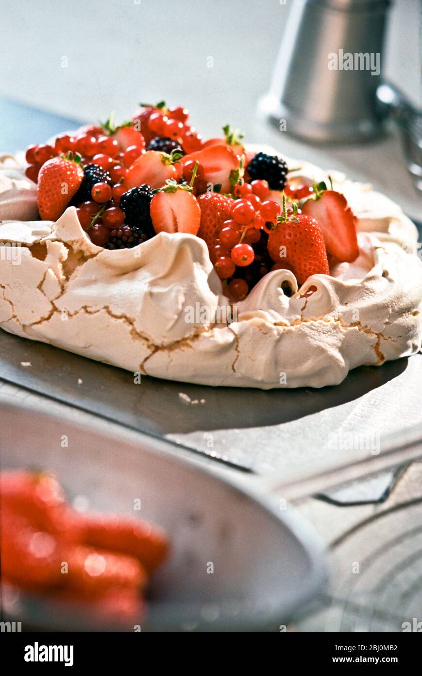 Pavlova with fresh berries on kitchen worktop - Stock Photo