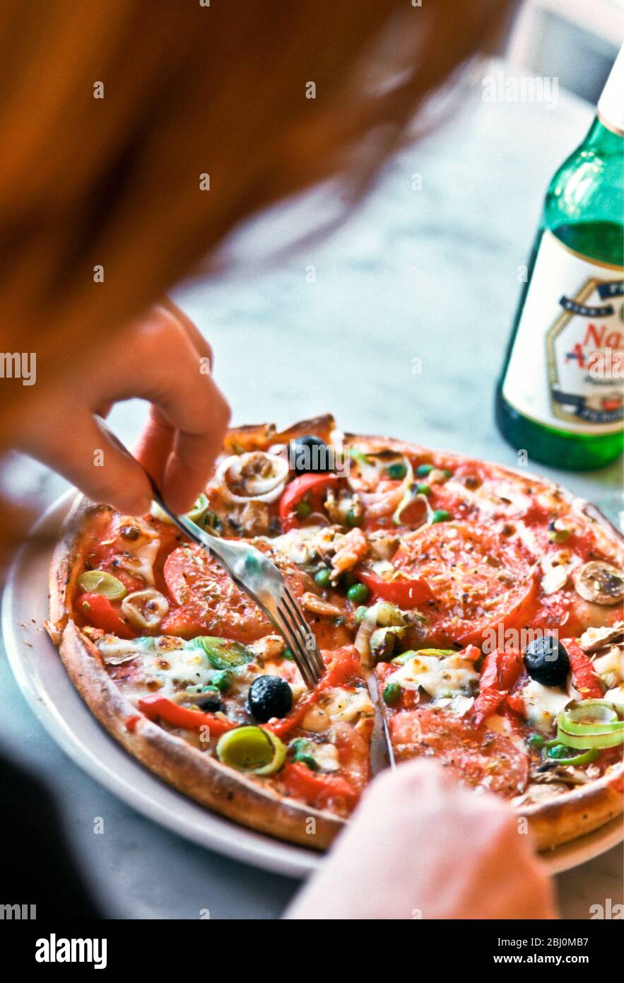 Eating pizza in Pizza Express restaurant, with bottle of Nastro Azzuro beer. - Stock Photo
