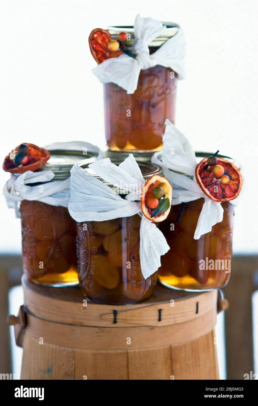 Jars of spiced dried apricots in brandy, decorated as christmas gifts. - Stock Photo