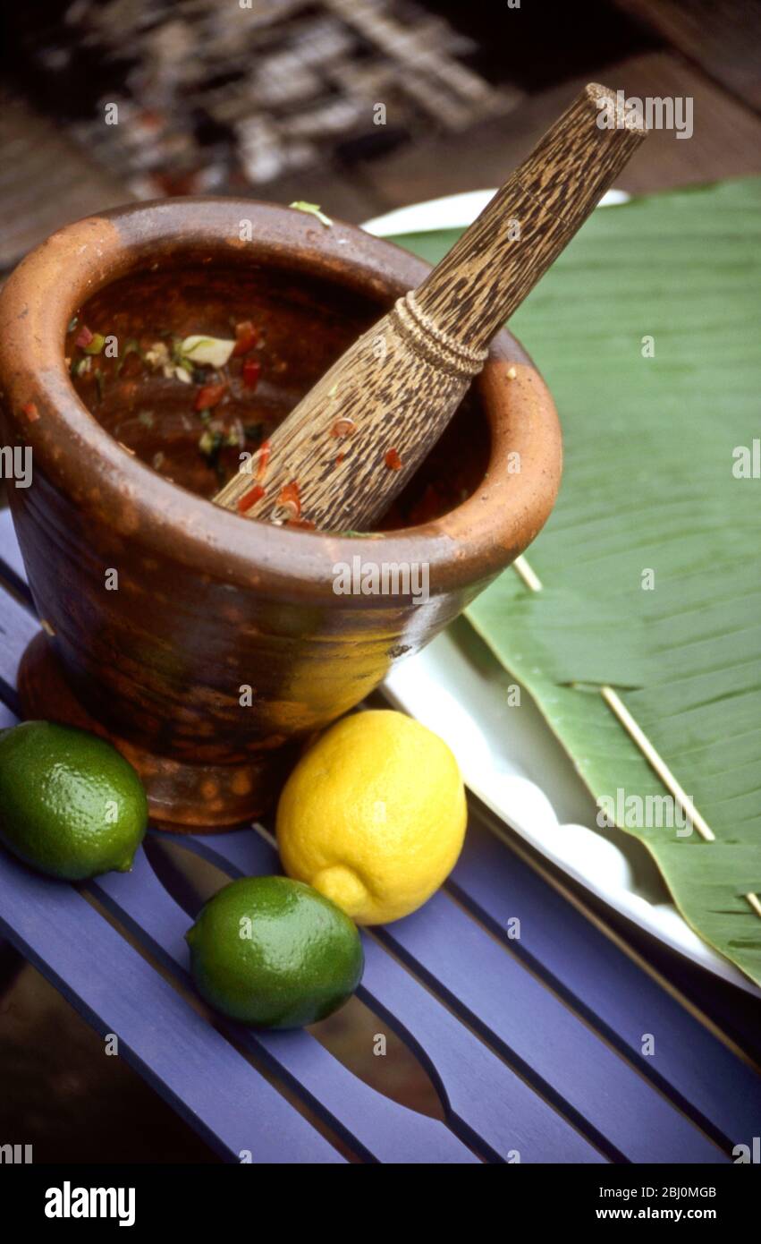 Salsa being mixed in heavy ethnic pestle and mortar outdoors - Stock Photo