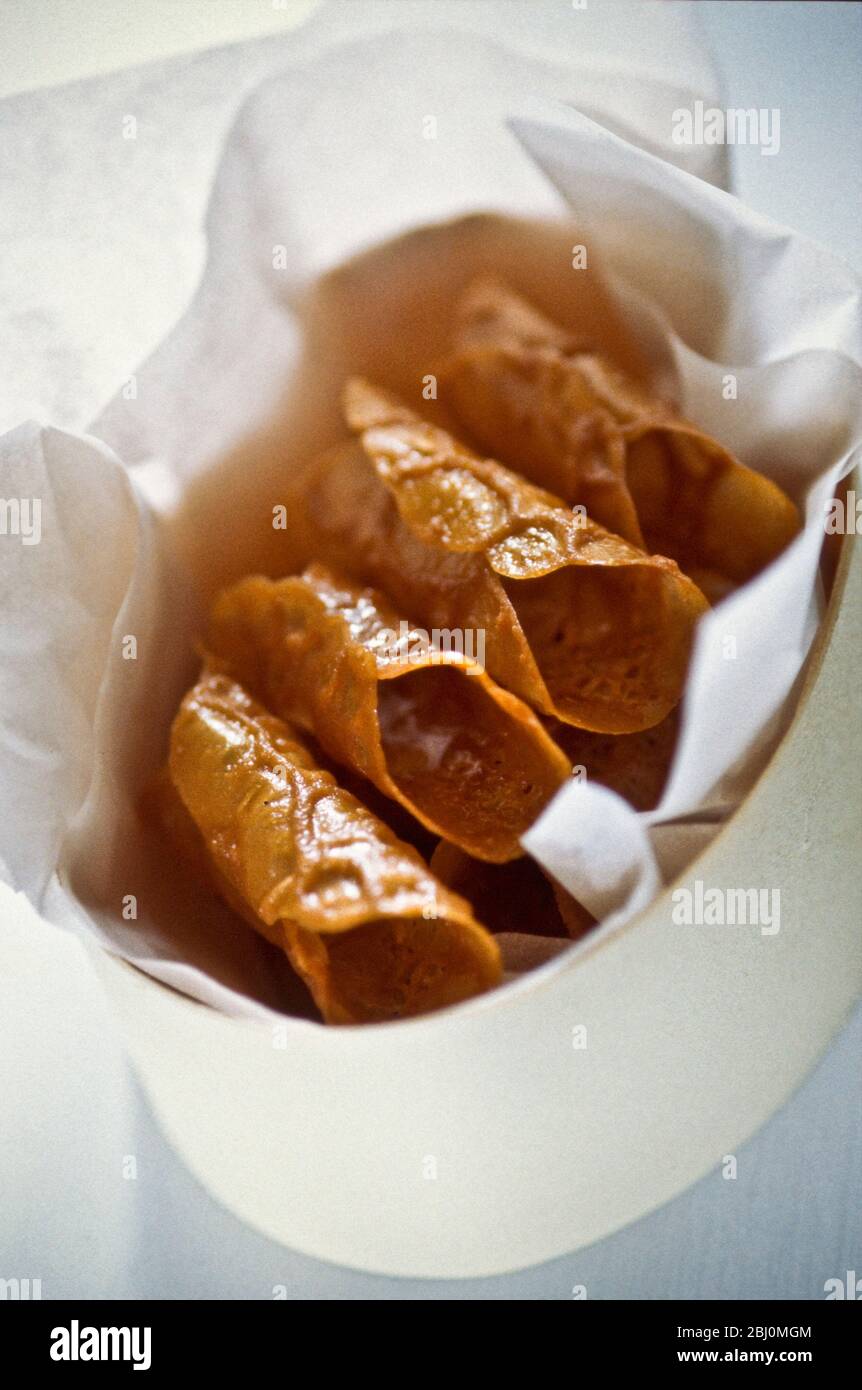 Home made brandy snap biscuits, packed into oval shaker box lined wih tissue paper as a gift. - Stock Photo