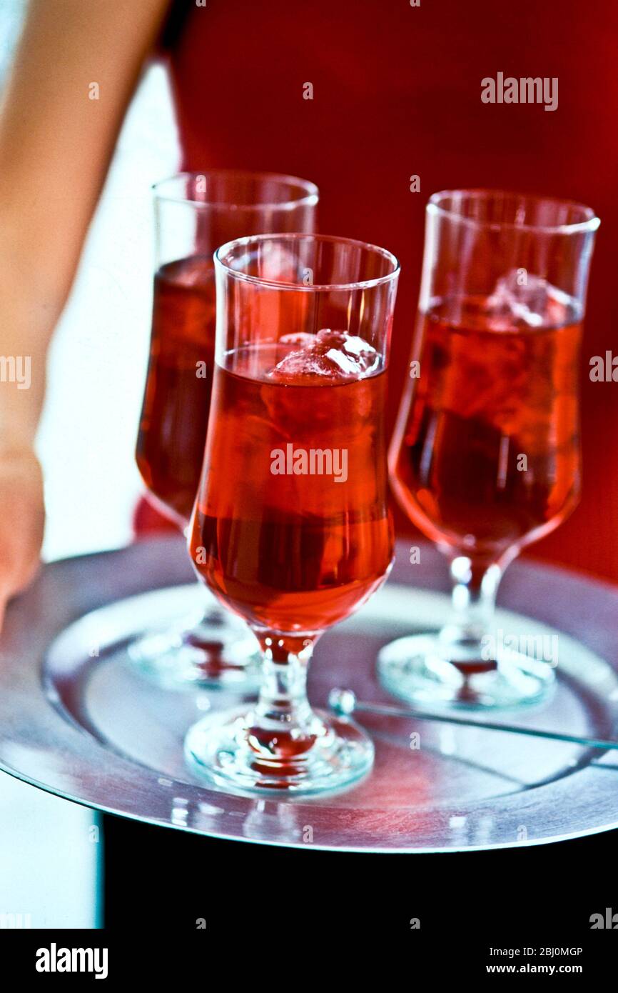 Tray of Bear's paw cockails carried by girl in red dress - Stock Photo