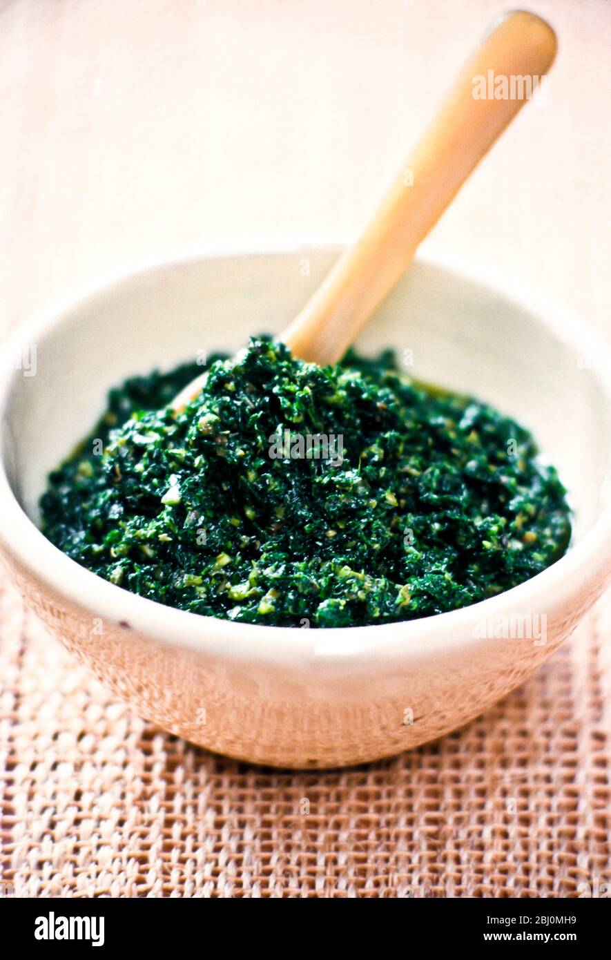 Small bowl of coarse homemade pesto with horn spoon - Stock Photo