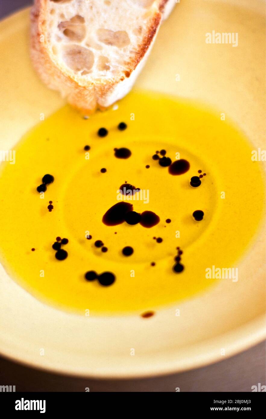 Olive oil with balsamic vinegar in yellow pottery dish with ciabatta bread - Stock Photo