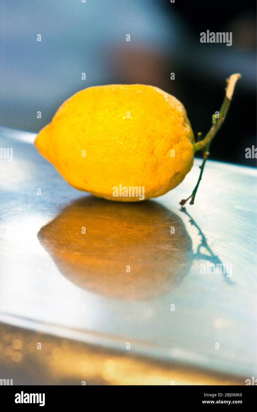 Single yellow lemon on stainless steel counter - Stock Photo