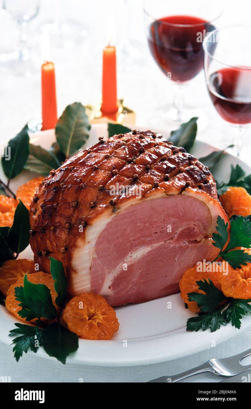 Honey glaze ham with cloves and oranges on white plate. - Stock Photo