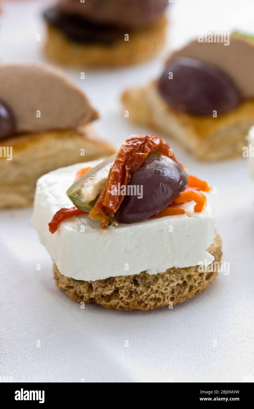 Canape of goat's chese with halved olive and sundried tomatoes on round croute - Stock Photo
