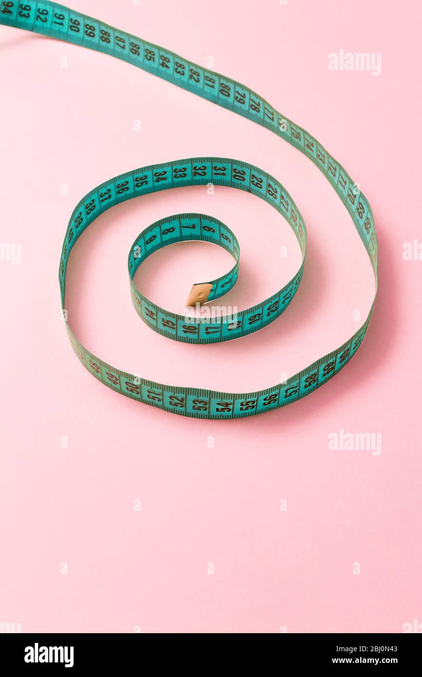 Spiral tailor measuring tape on pink background Stock Photo