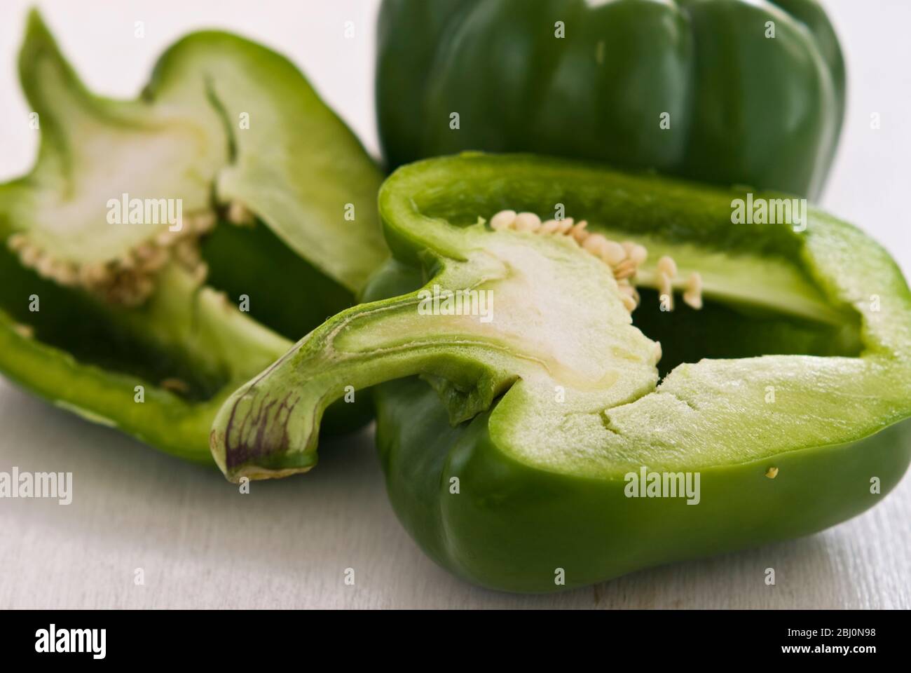 Shiny green sweet peppers, whole and cut in half. - - - Stock Photo