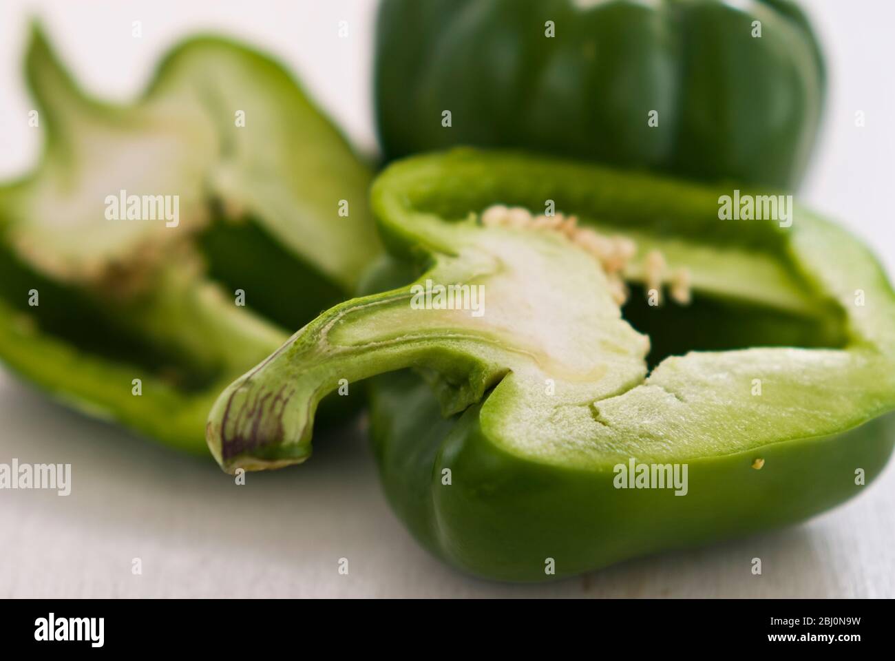 Sweet green peppers, whole and cut in half. - Stock Photo