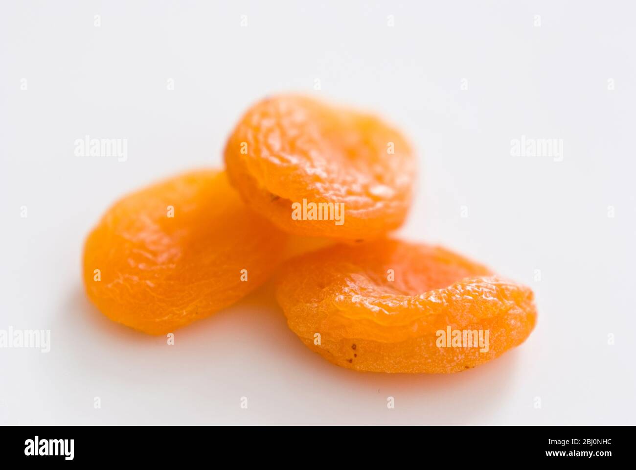 Three dried apricots on white surface - Stock Photo