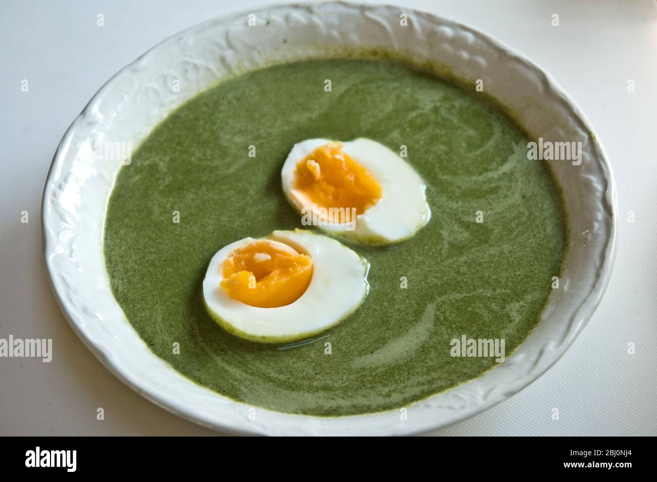 Traditional Swedish springtime soup made of nettles and chicken stock with a boiled egg halved on top - Stock Photo