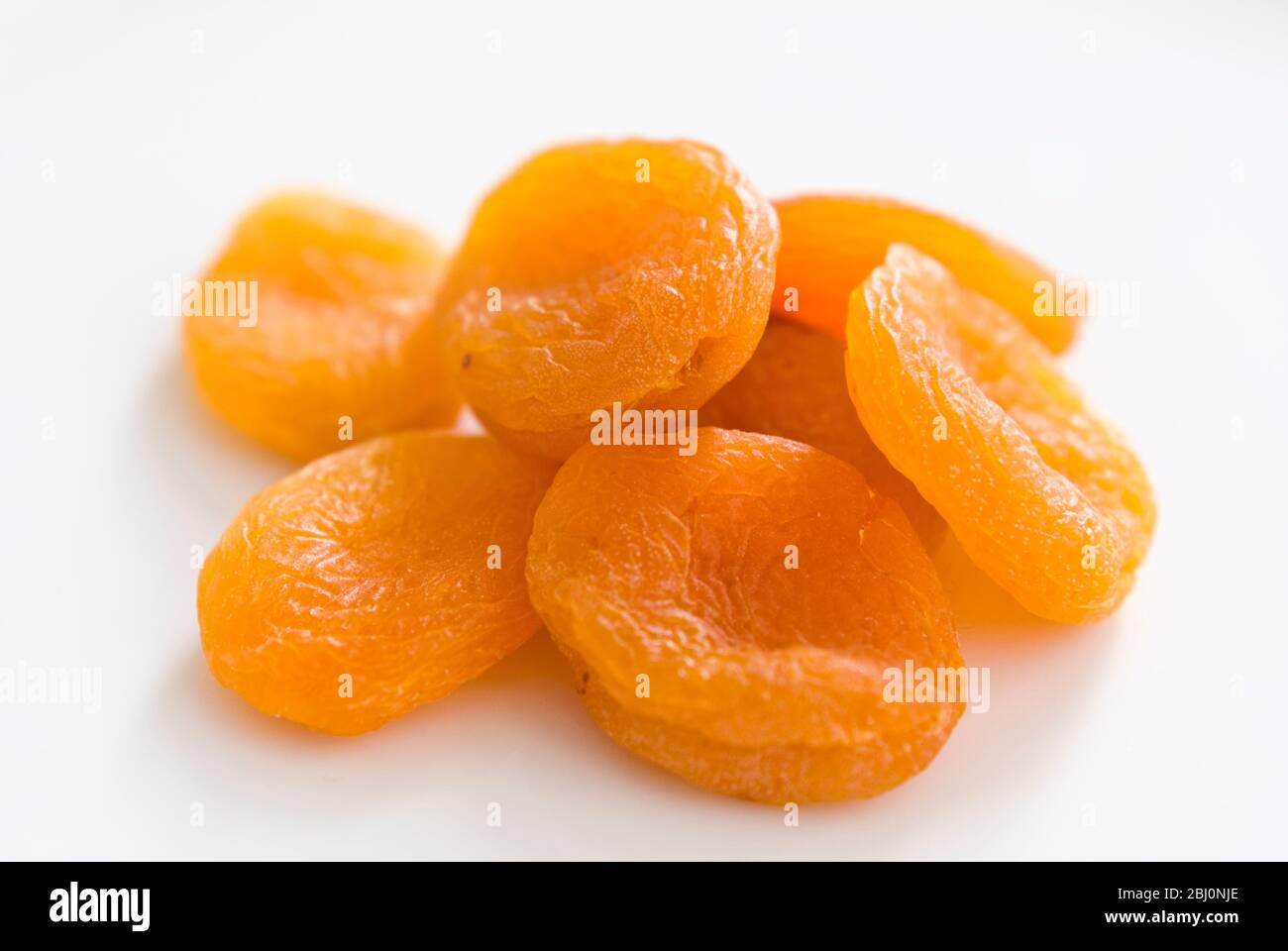 Small pile of dried apricots on white surface - Stock Photo