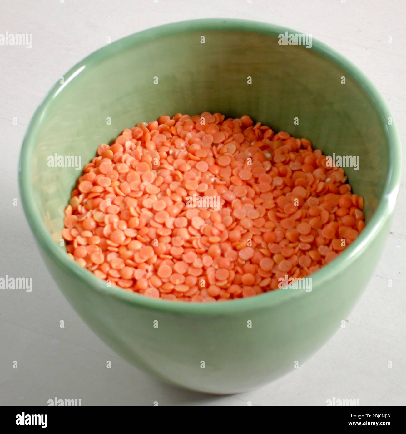 Pottery bowl of raw red split lentils - Stock Photo