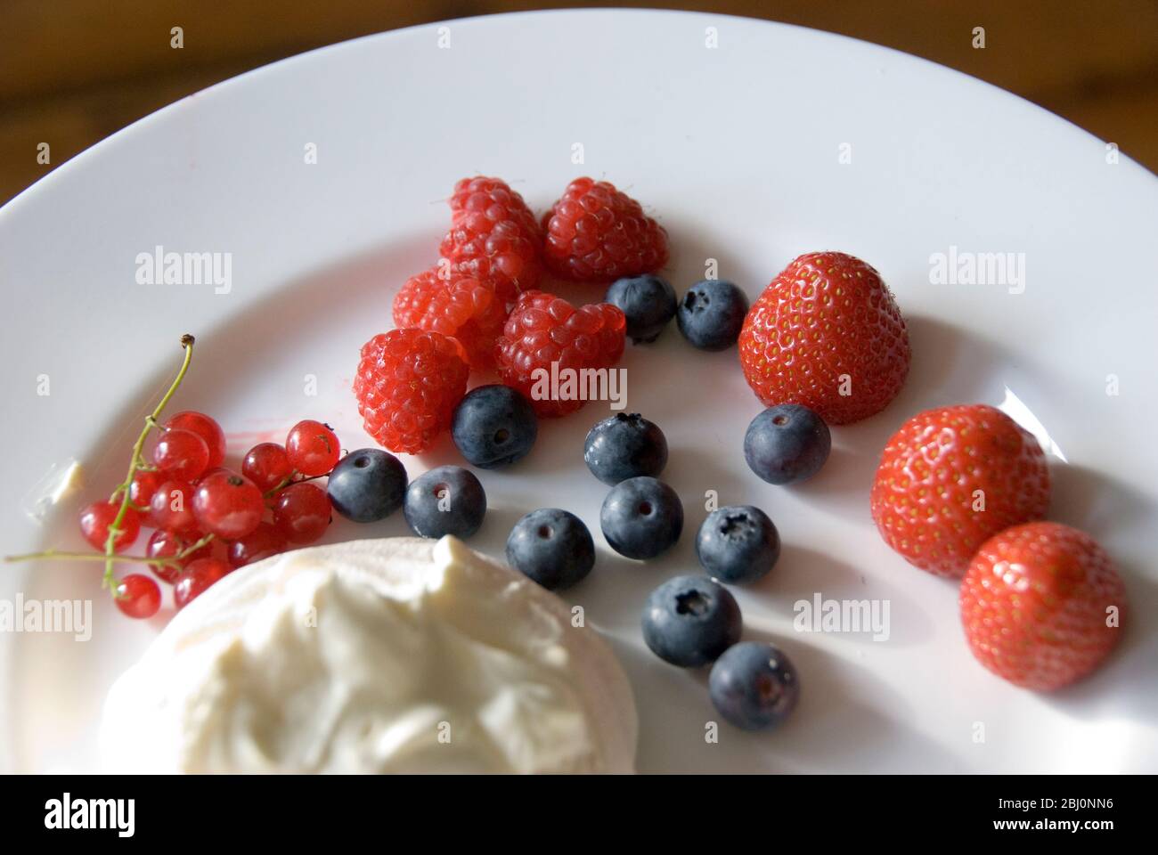 Light summer dessert of fresh berries with whipped cream mixed with yoghurt - Stock Photo