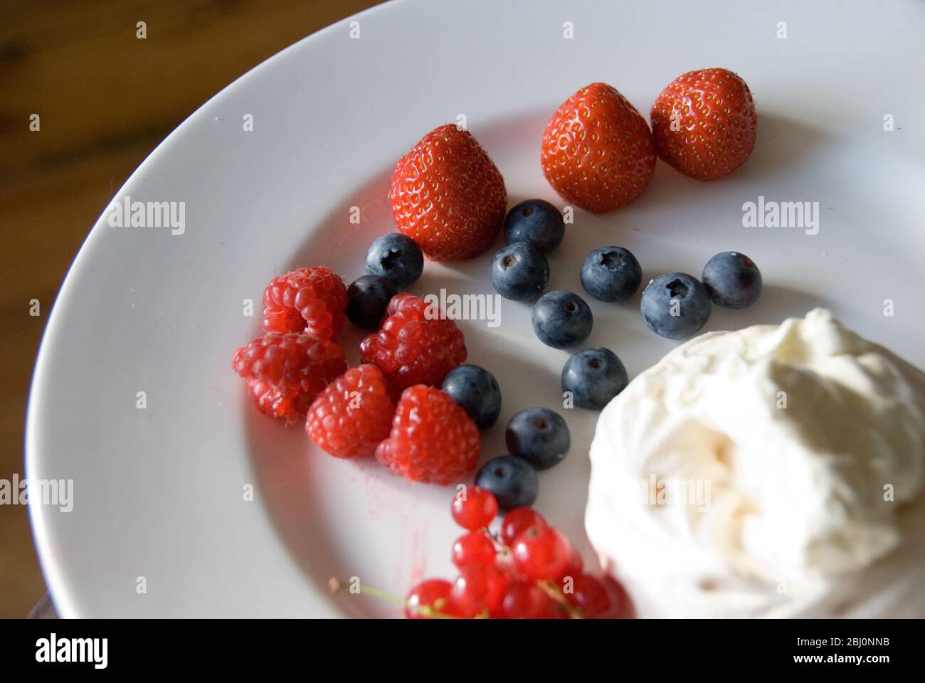 Light summer dessert of fresh berries with whipped cream mixed with yoghurt - Stock Photo