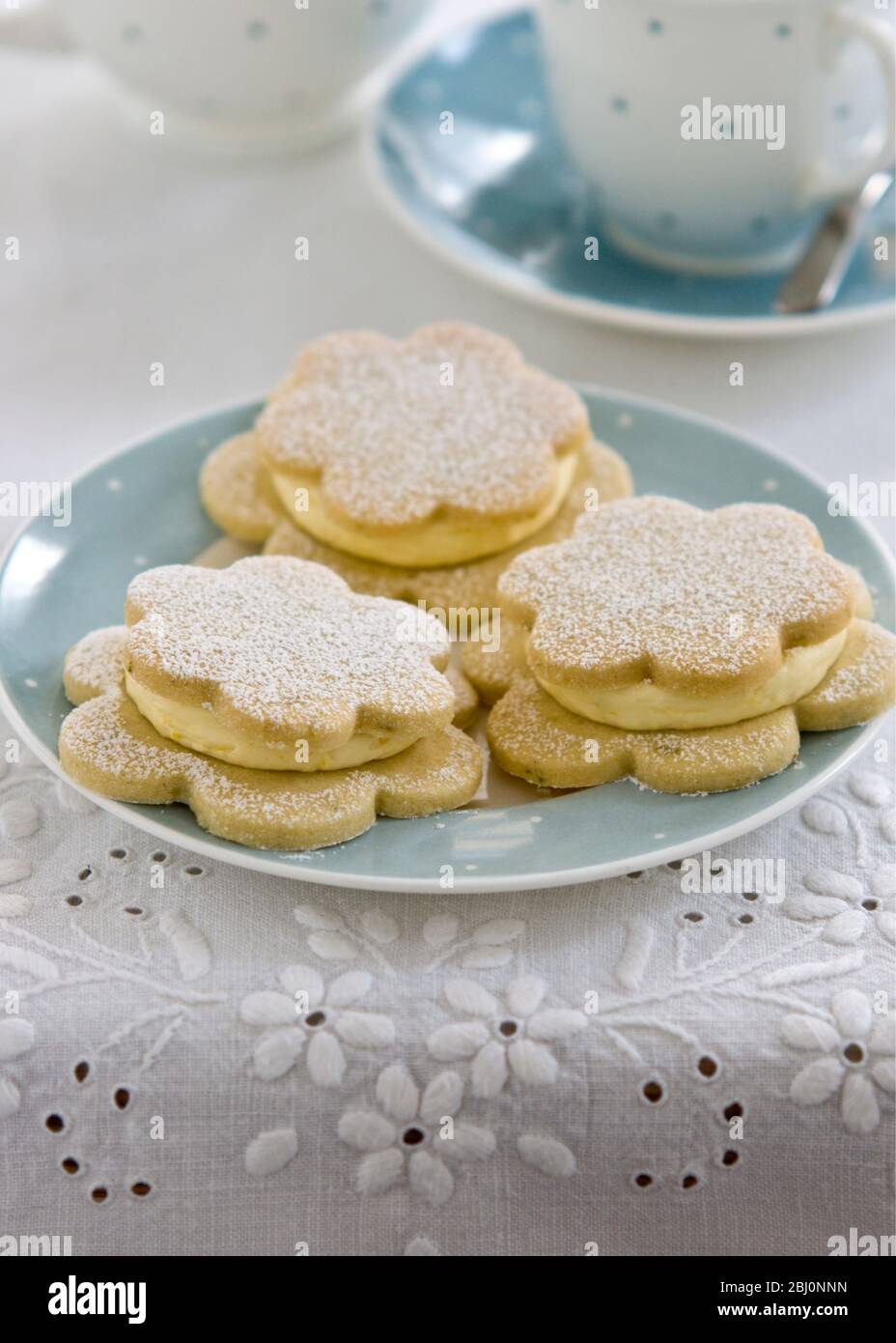 Pretty flower shaped biscuits sandwiched together with vanilla buttercream - Stock Photo