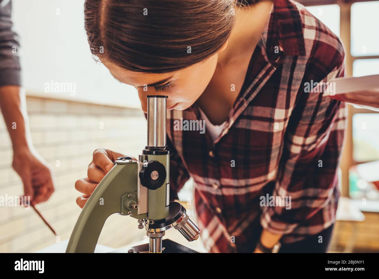 Girl looking at slides in biology class through a microscope. High ...