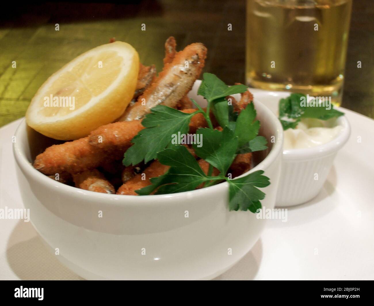 Deep fried whitebait, with lemon wedge and mayonnaise, garnished with flat parsley. - Stock Photo