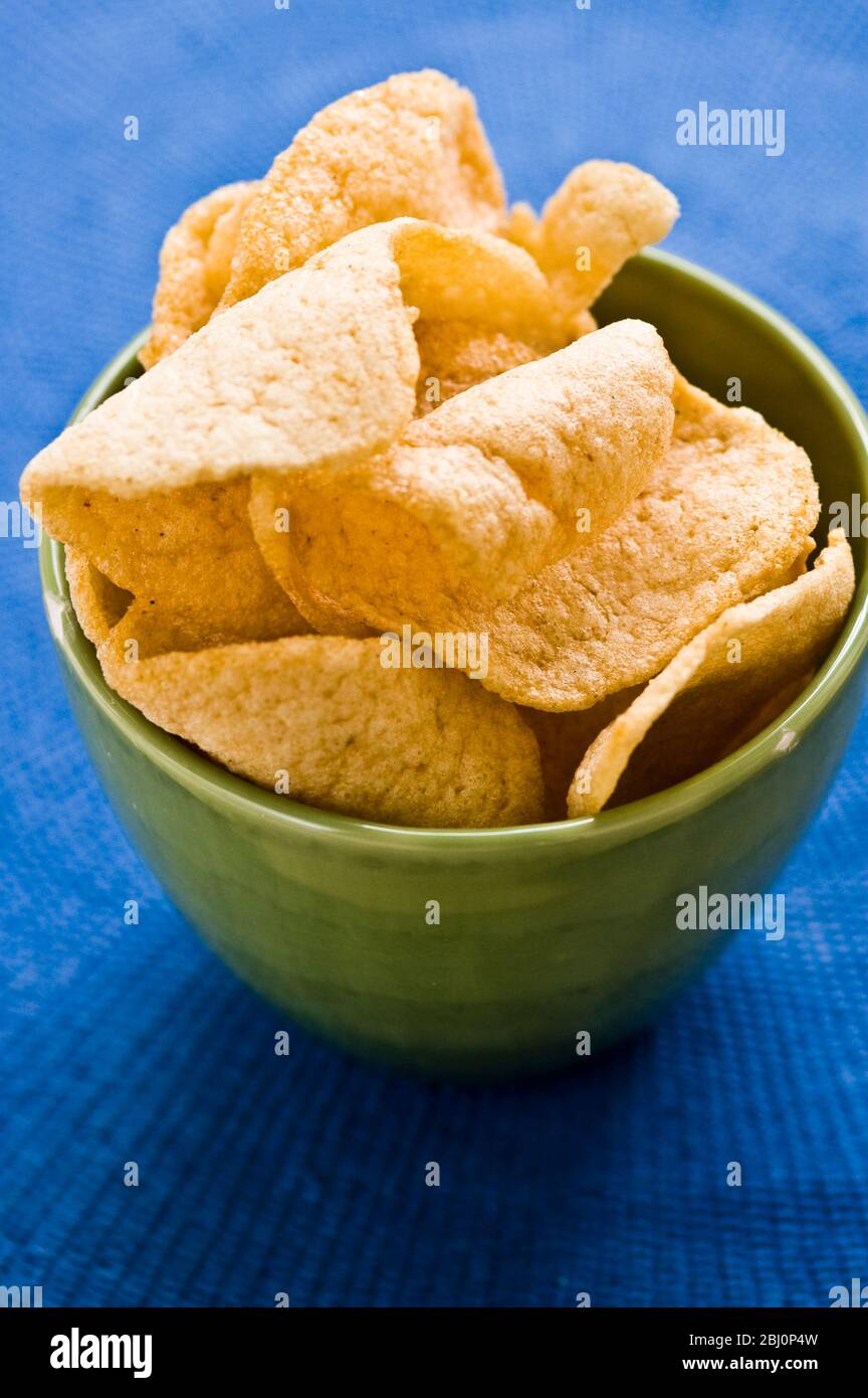 Thai prawn crackers in green pottery bowl on blue cloth - Stock Photo